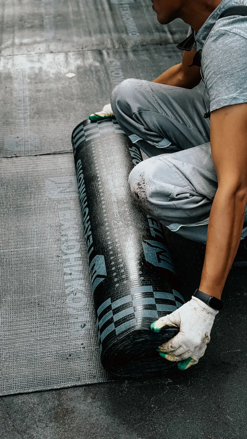 Gloved hands unrolling roofing membrane