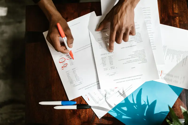 Two people marking up a printed estimate with a red pen